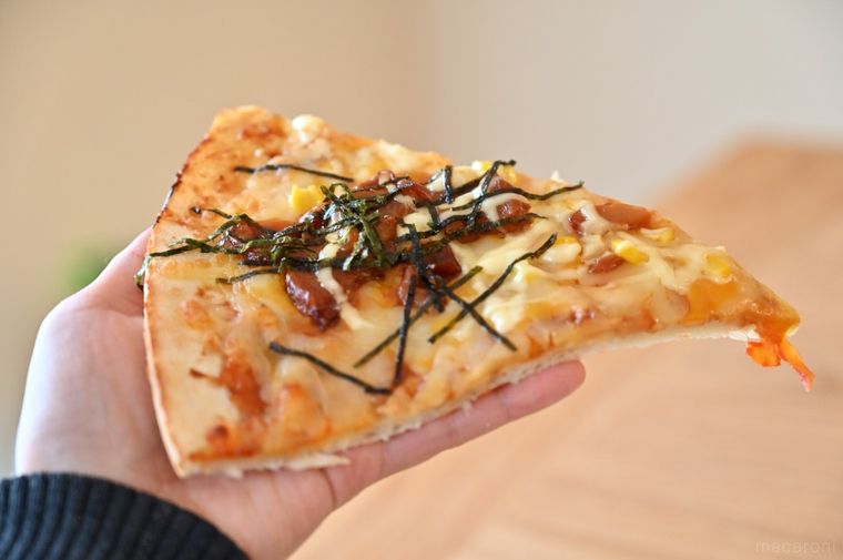 手のひらにのせたMEGAサイズの照り焼きチキンマヨピザひと切れ