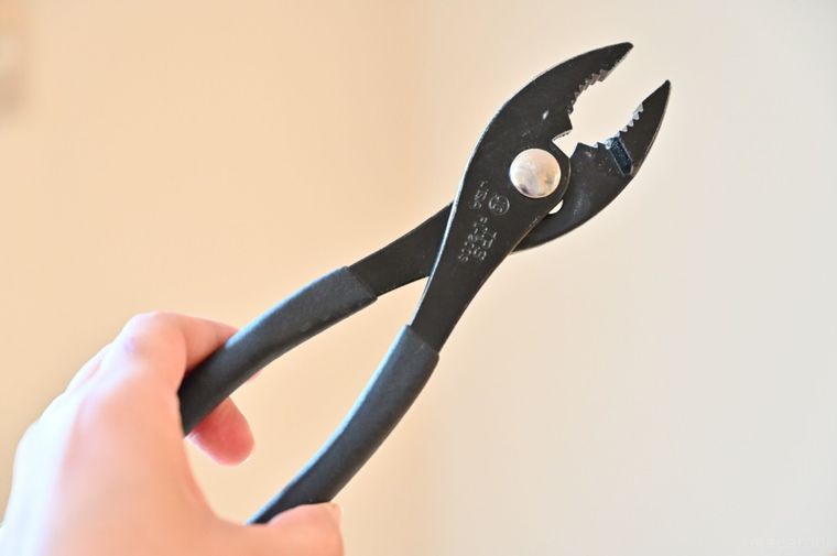 黒いペンチを手に持っている