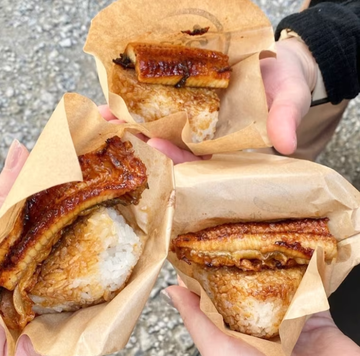 3人がそれぞれ浅草うななのうなぎのおにぎりを手に持っている