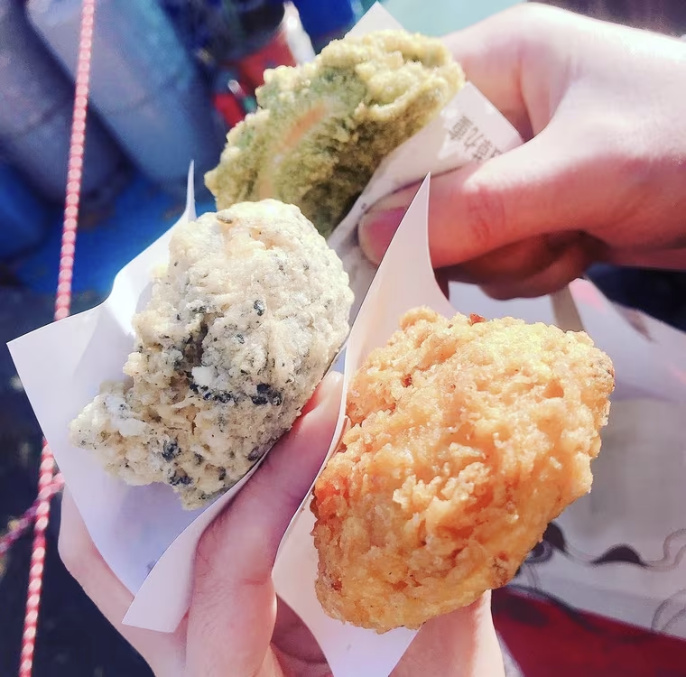 味の違うあげまんじゅうを両手で3つ持っている