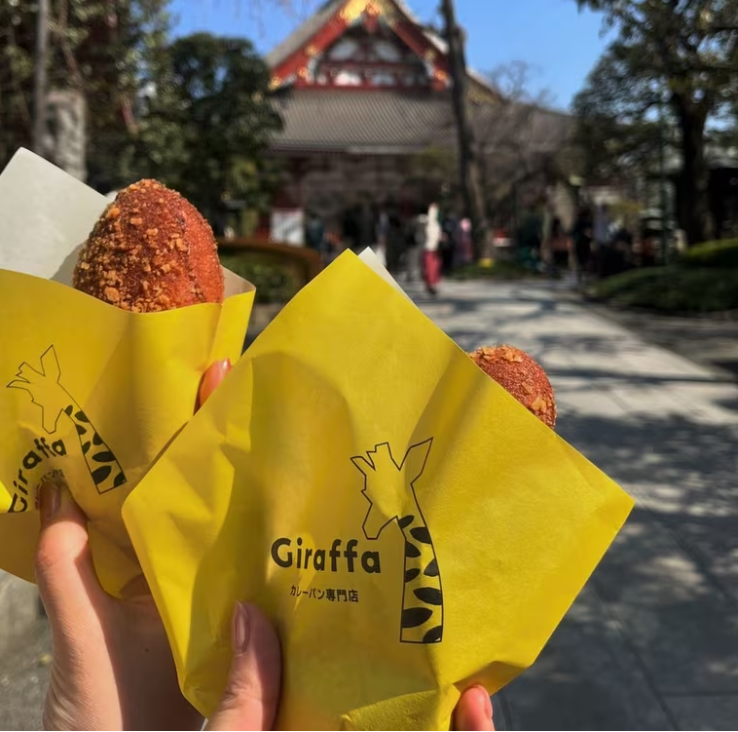 ふたりが片手でひとつずつジラッファのカレーパンを持ってる