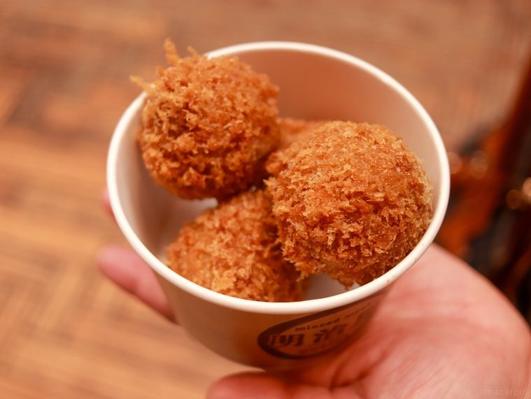 小さな丸いメンチカツがカップに4つ入ったまるころミンチを手のひらにのせている
