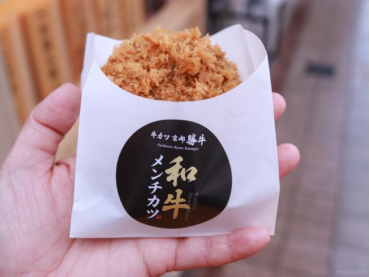 京都勝牛の店頭で和牛メンチカツを手に持っている