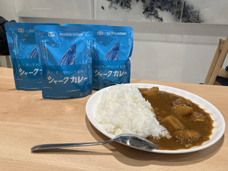 白いお皿に盛られたシャークカレーと青色のパッケージが並んでいる