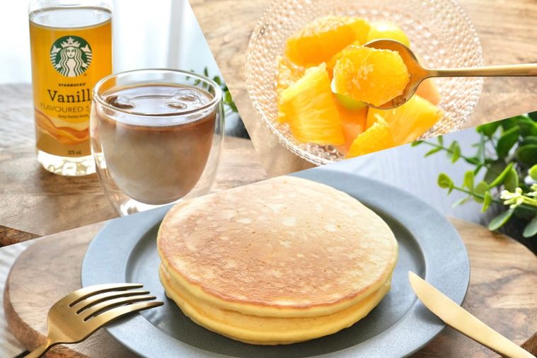 グレーの皿に盛られた2段重ねのパンケーキとフルーツカクテルとアイスカフェラテとバニラフレーバーシロップのボトル