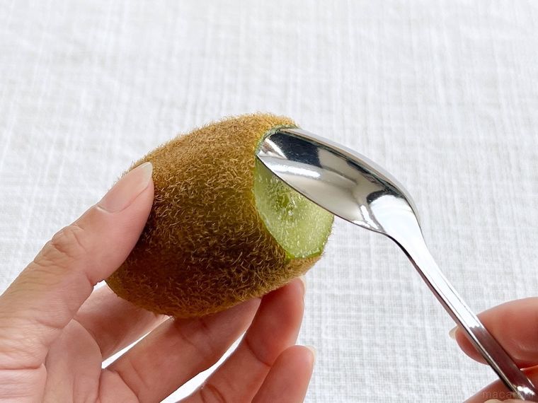 キウイにスプーンを差し込んでいる様子