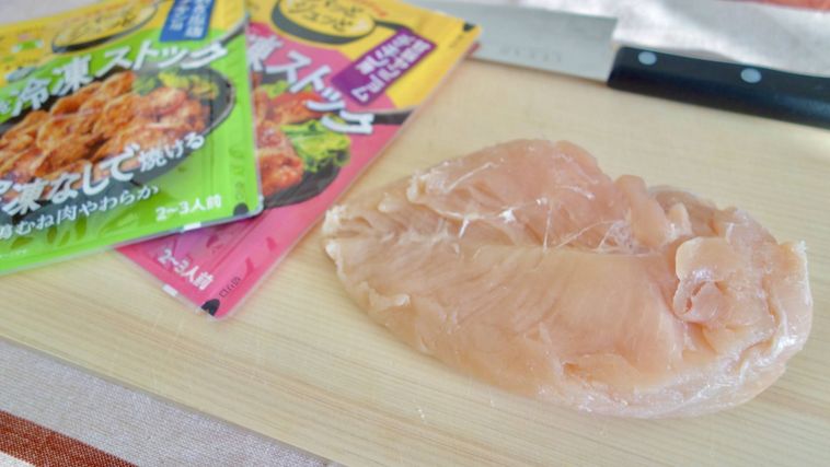 パッとジュッと®の外袋と鶏むね肉、包丁がまな板に置かれている