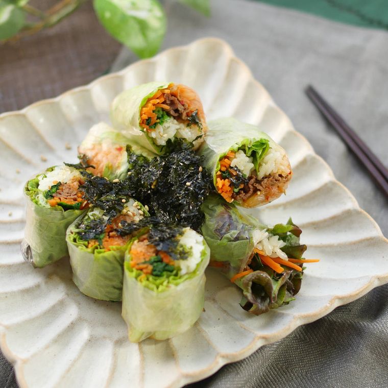 陶器の角皿に入った牛肉とにんじん、ほうれん草の生春巻き