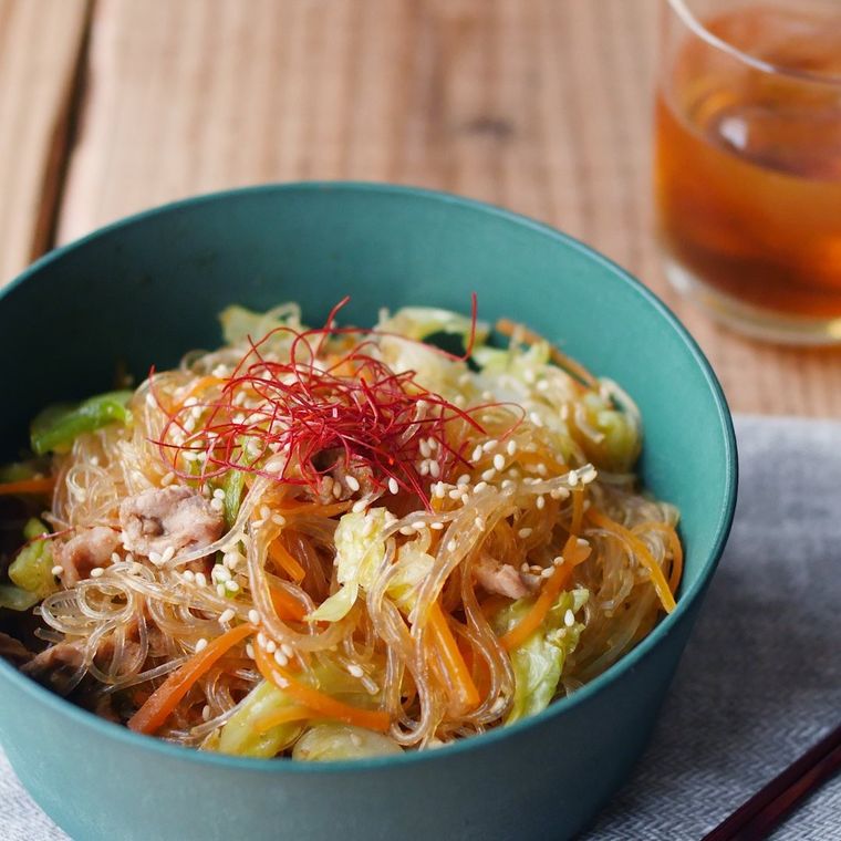緑の器に入った春雨やにんじん、豚肉のチャプチェ