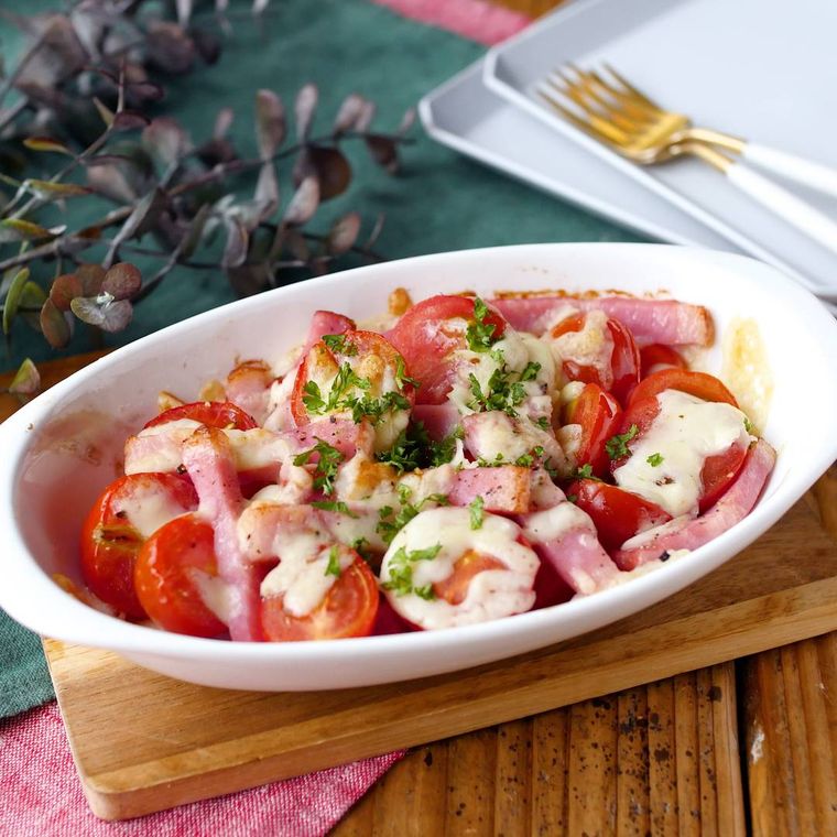 白い皿に盛り付けられたミニトマトとベーコンのチーズ焼き