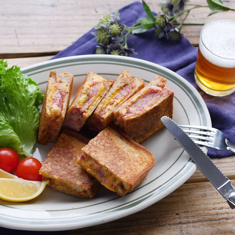 白い楕円形の皿に盛り付けたコンビーフポテトのホットサンド