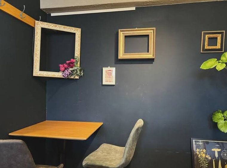 黒い壁に額縁が飾られたクルールキタロクのテーブル席