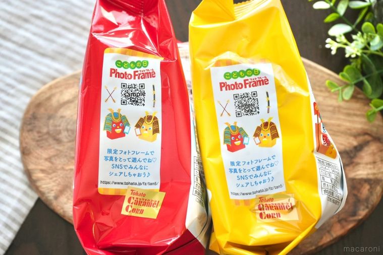 木のカッティングボードにのった赤と黄色の端午の節句限定パッケージのキャラメルコーンとパッケージ側面のQRコード