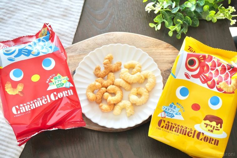 木のカッティングボードと白い皿にのったキャラメルコーンと赤と黄色の端午の節句のこいのぼりパッケージとストライプの布