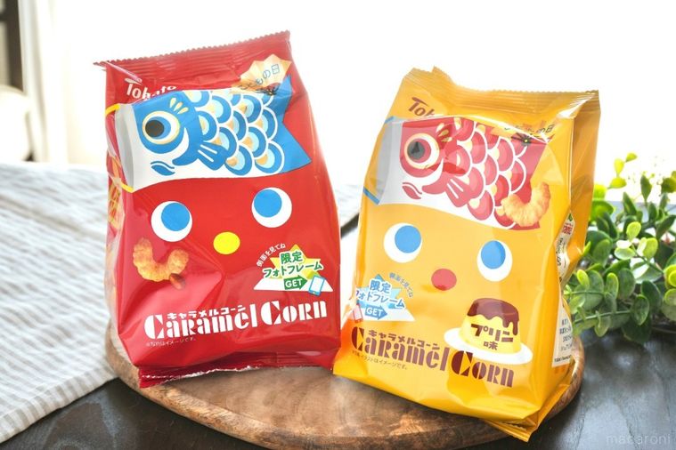 木のカッティングボードにのった赤と黄色の端午の節句バージョンのキャラメルコーンとストライプの布とグリーン