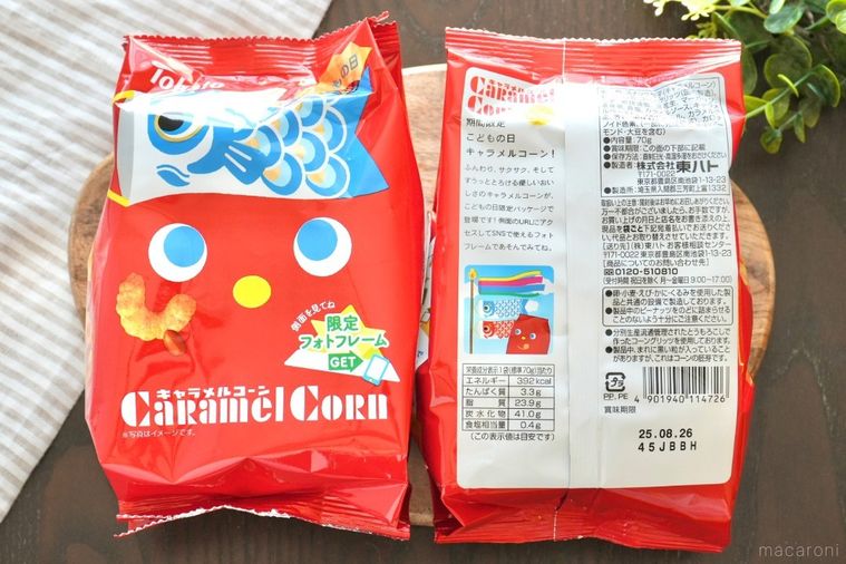 木のカッティングボードにのった赤い端午の節句バージョンのキャラメルコーンのこいのぼりパッケージとストライプの布