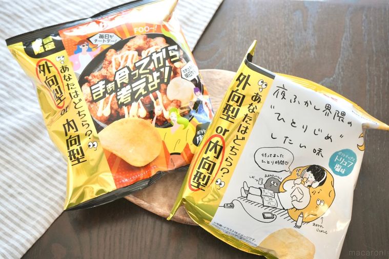 木のカッティングボードにのった2種類のポテトチップスの袋とストライプの布