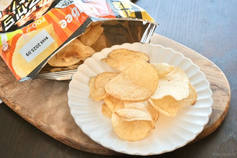 木のカッティングボードと白い皿にのった唐揚げマヨ味のポテトチップスとパッケージ