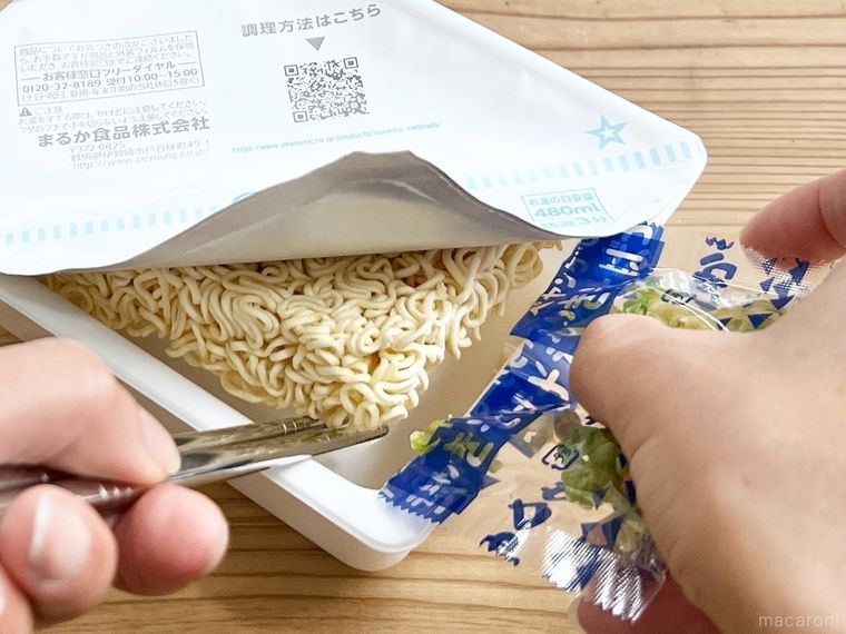 カップ焼きそばにかやくを入れようとしている様子