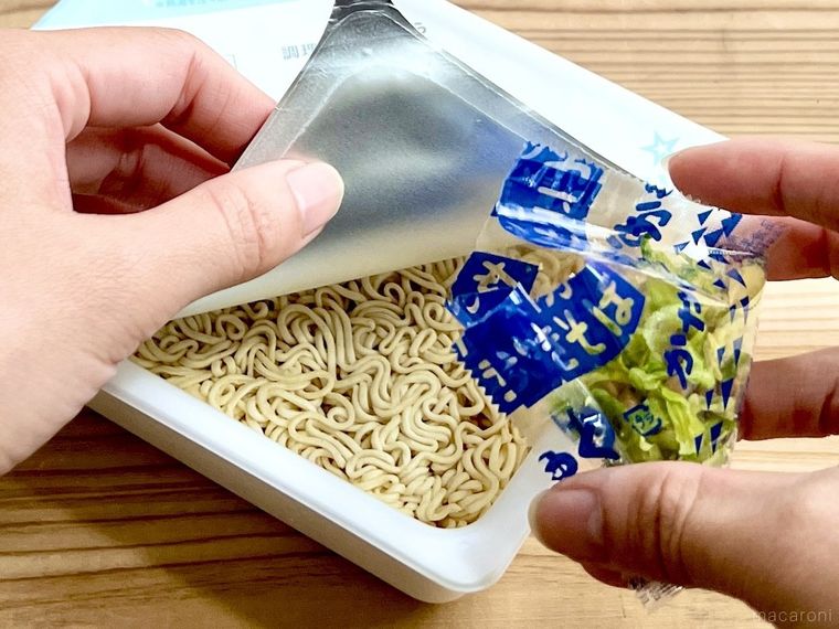 カップ焼きそばにかやくを入れようとしている様子