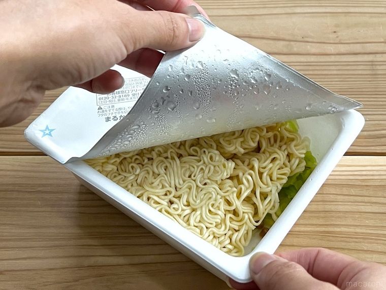 カップ焼きそばのフタを開けている様子