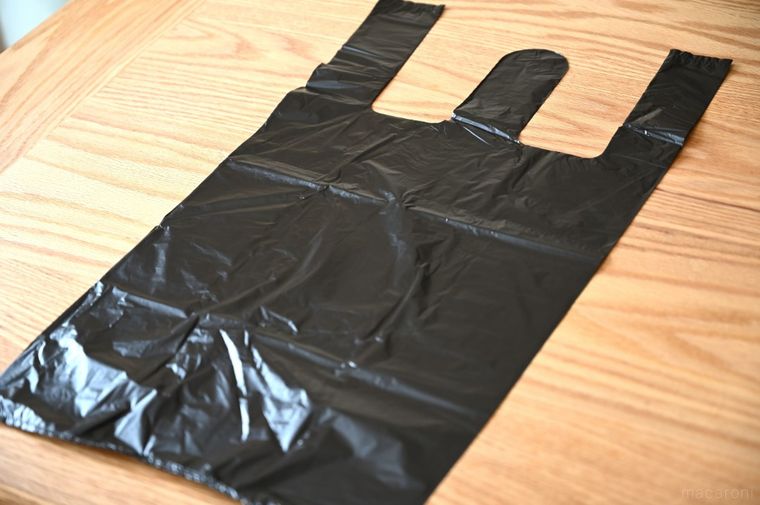 木のテーブルに広げた持ち手付きの黒い袋