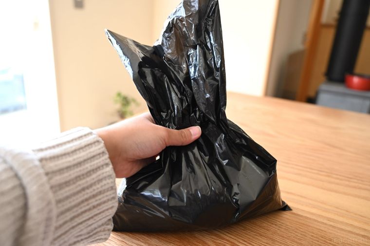 使用済みおむつを入れた黒い袋を手に持っている