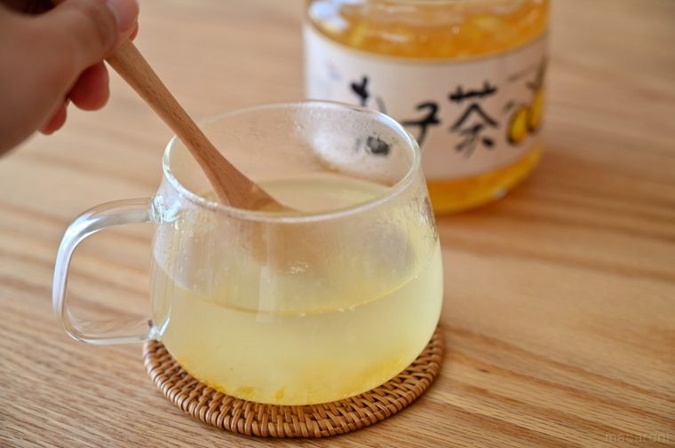 グラスに入ったホットゆずを木のスプーンでかき混ぜている