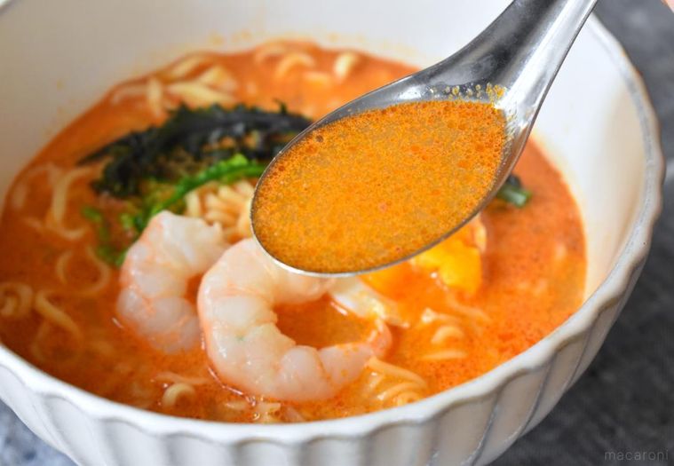 れんげですくったトムヤムクンクリーミーヌードルのスープ