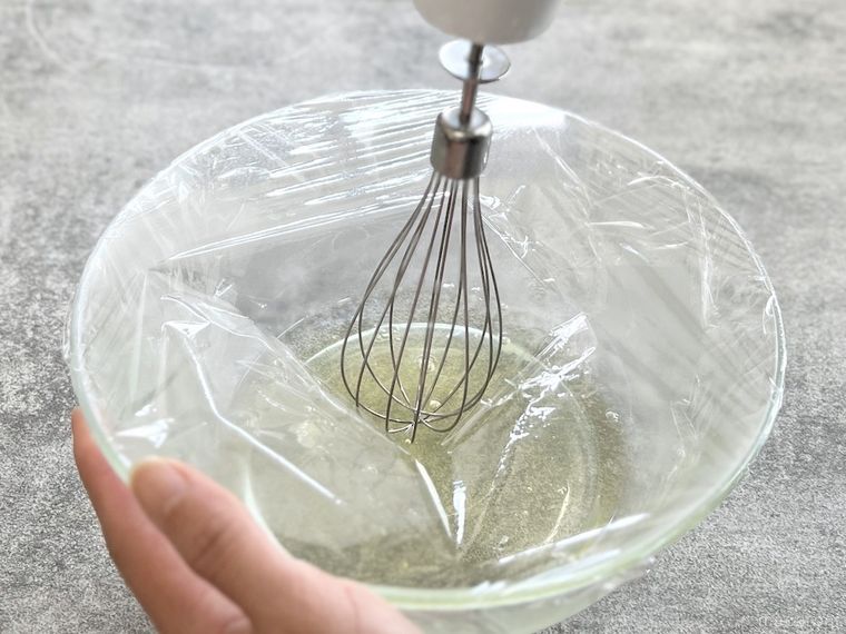 ラップをかけたボウルで卵白を泡だてようとしている様子