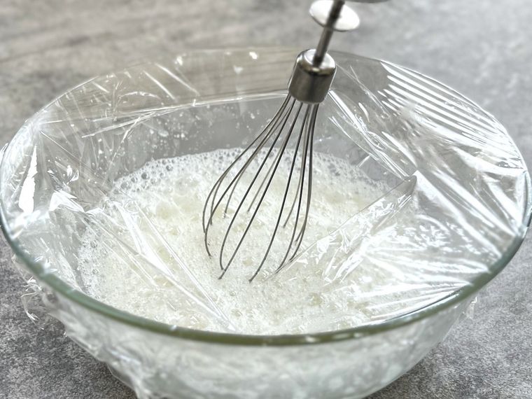 ラップをかけたボウルで卵白を泡だてている様子