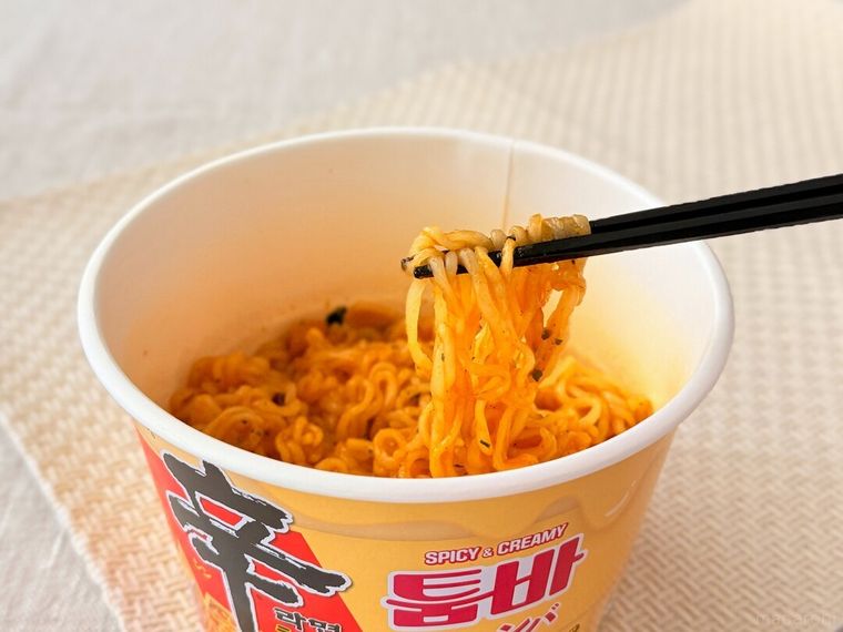 「辛ラーメン トゥーンバ カップ」の麺を箸で持っている様子