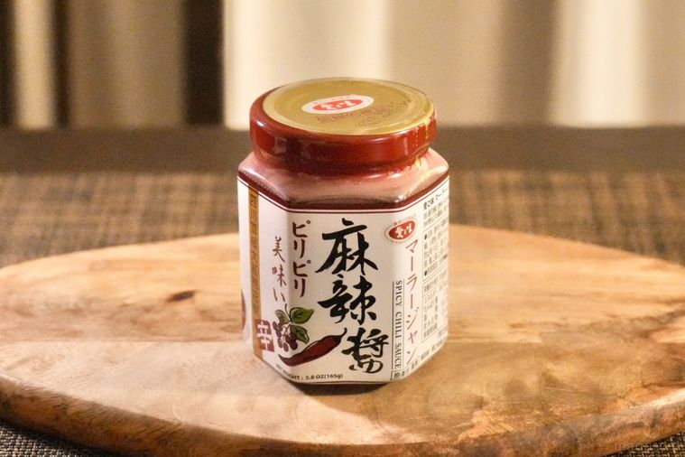 茶色いランチョンマットと木のカッティングボードにのった麻辣醤の瓶