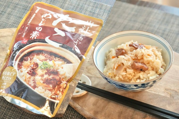 木のカッティングボードにのったたこめしの入った茶碗と黒い箸と炊き込みご飯の素