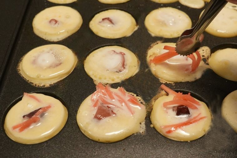 たこ焼き器に生地と具材をのせて焼く様子