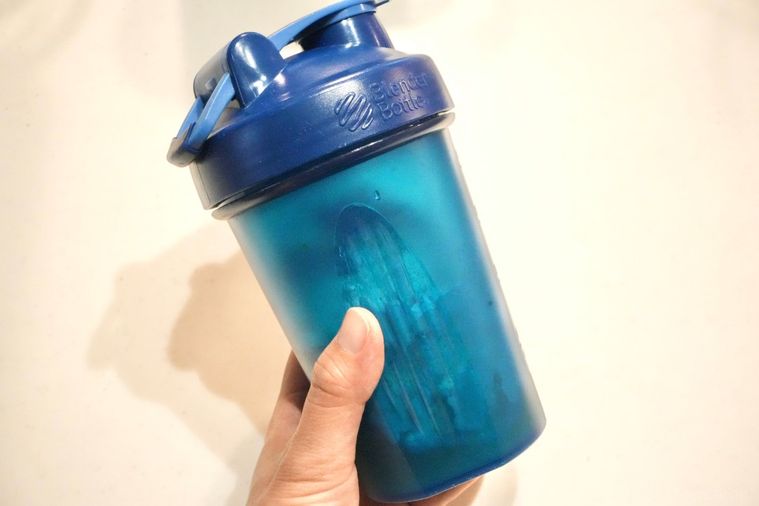 青いプロテインシェイカーを振る様子