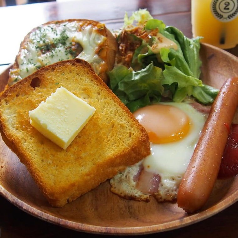 ベーコンエッグとソーセージ、サラダ、バター添えのトーストがのったモーニング