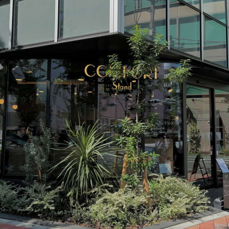 大きな観葉植物に囲まれたコンフォートスタンドのおしゃれな外観