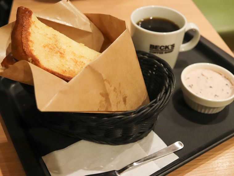 黒いトレーに白いカップに入ったホットコーヒーと小倉クリームチーズホイップ、かごに入ったトーストが置かれている