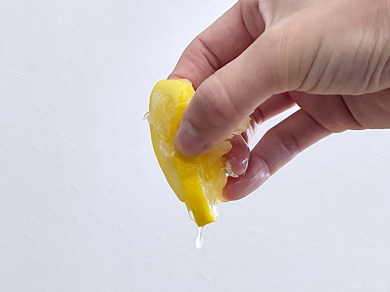 スライスレモンを手で搾っている様子