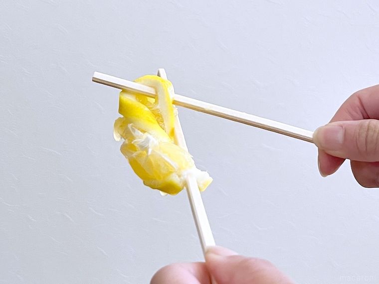 スライスレモンを箸で搾っている様子