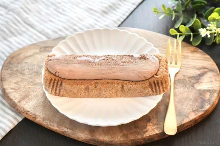 木のカッティングボードと白い皿にのったショコラクリームのせ生シフォンと金のフォークとストライプの布