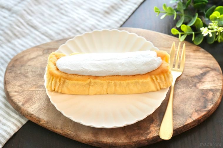 木のカッティングボードと白い皿にのった生クリームのせ生シフォンと金のフォークとストライプの布