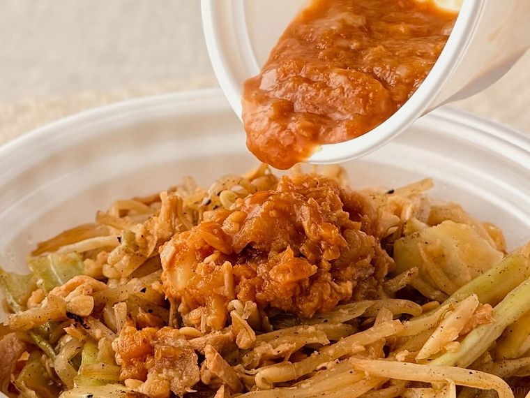 「ニンニク野菜牛めし」に別添えの背脂醤油ダレをかけている様子