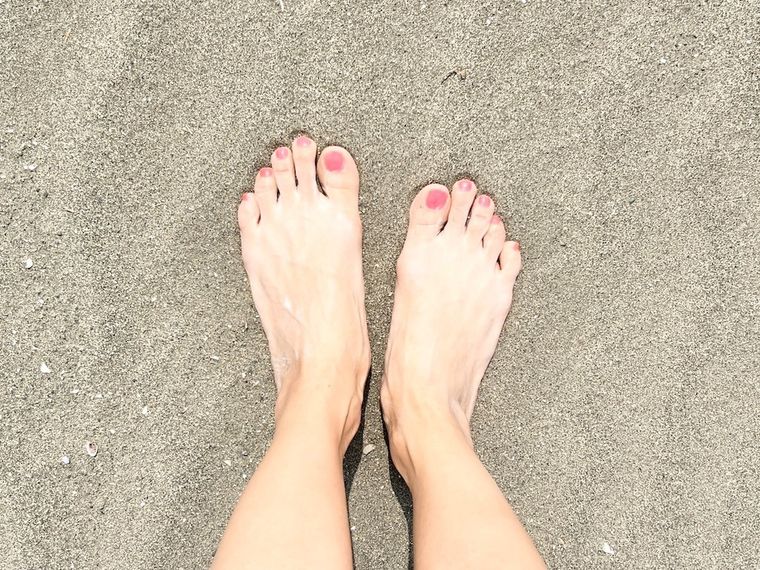 裸足で砂浜を歩いている様子