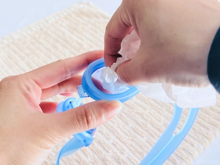 水泳用ゴーグルのレンズをティッシュで拭いている様子