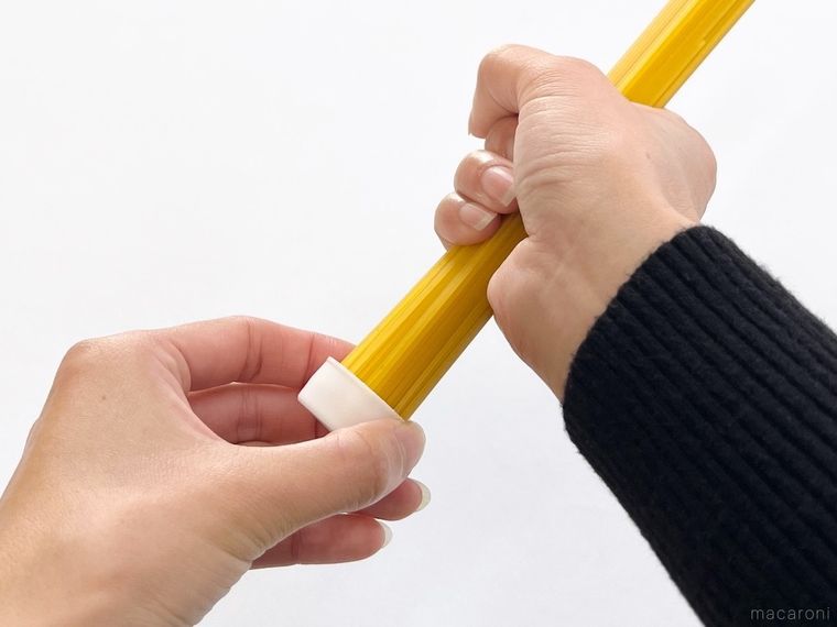 ペットボトルのキャップにパスタを差し込んでいる様子