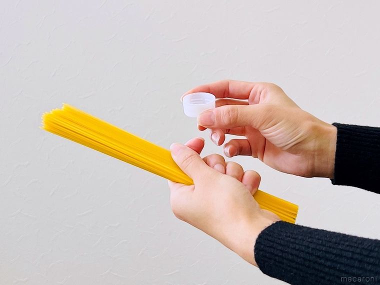 パスタとペットボトルのキャップを両手で持っている様子