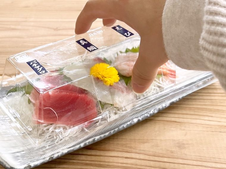 刺身パックのフタを外そうとしている様子