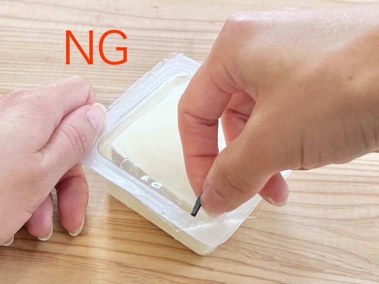 豆腐パックを開けようとしている様子